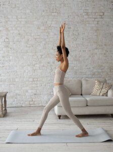 A woman in white pants and top doing yoga.