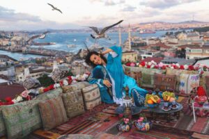 A woman sitting on the ground with birds flying over her.