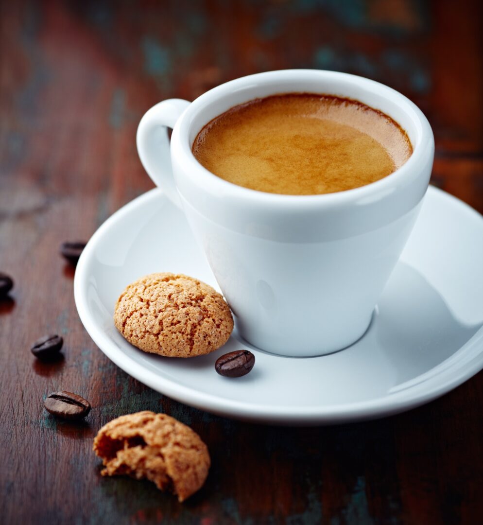 A cup of coffee and some cookies on a plate.