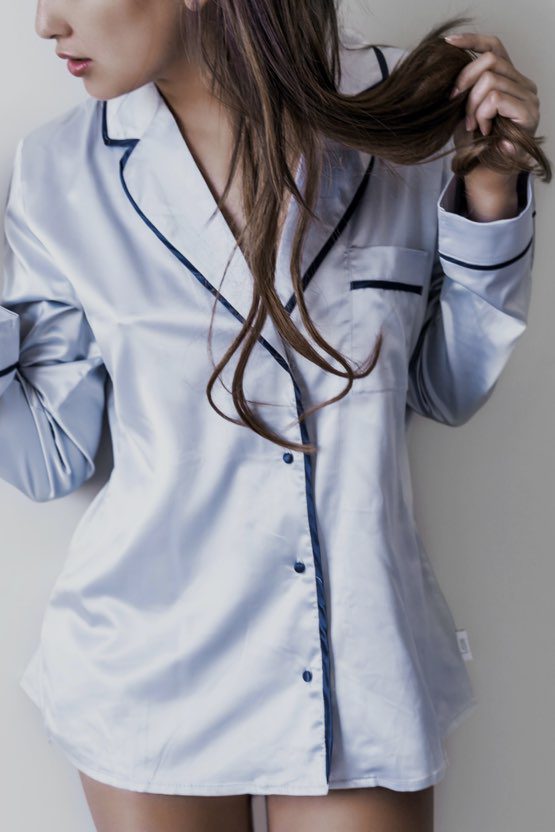 A woman in white shirt holding her hair.