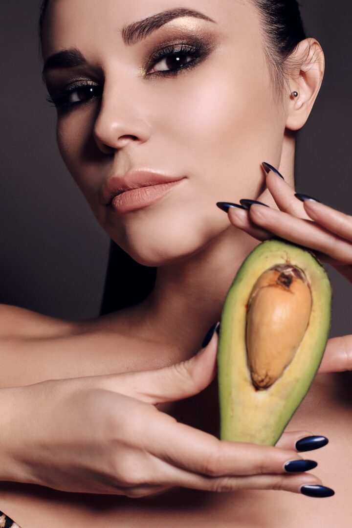 A woman holding an avocado in her hand.