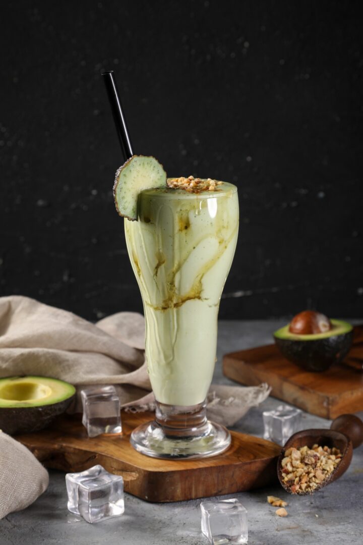 A glass of avocado smoothie with cucumber and nuts.