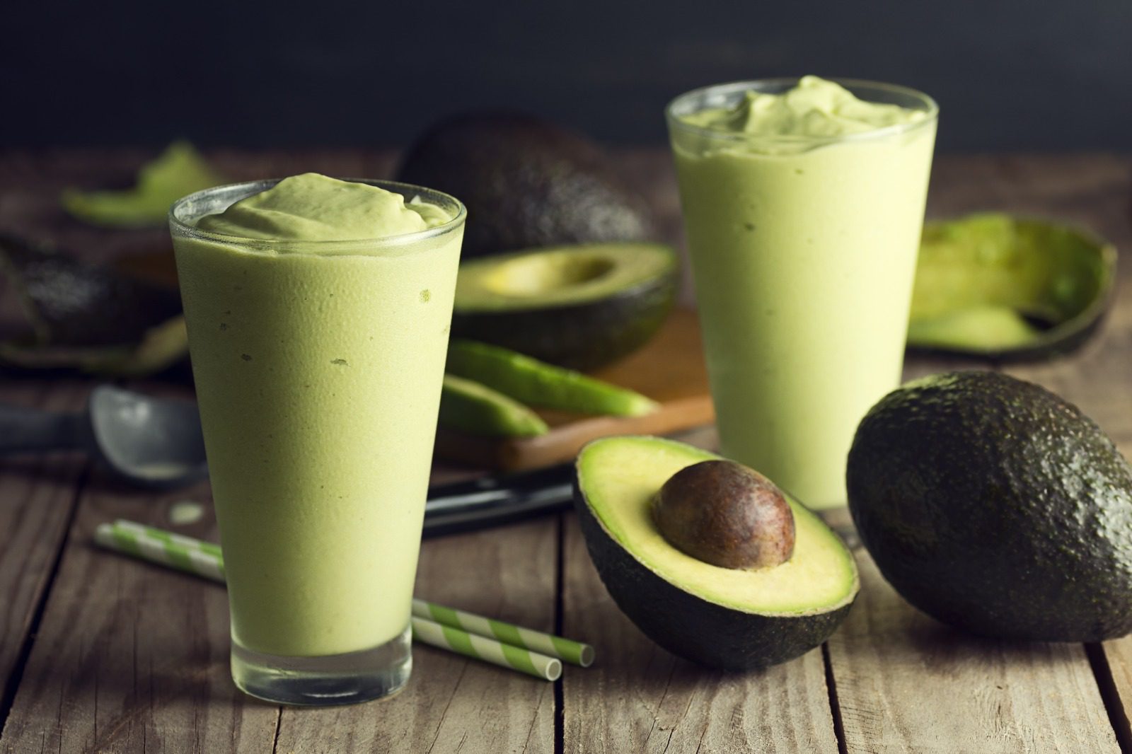 A wooden table with two glasses of avocado smoothie.