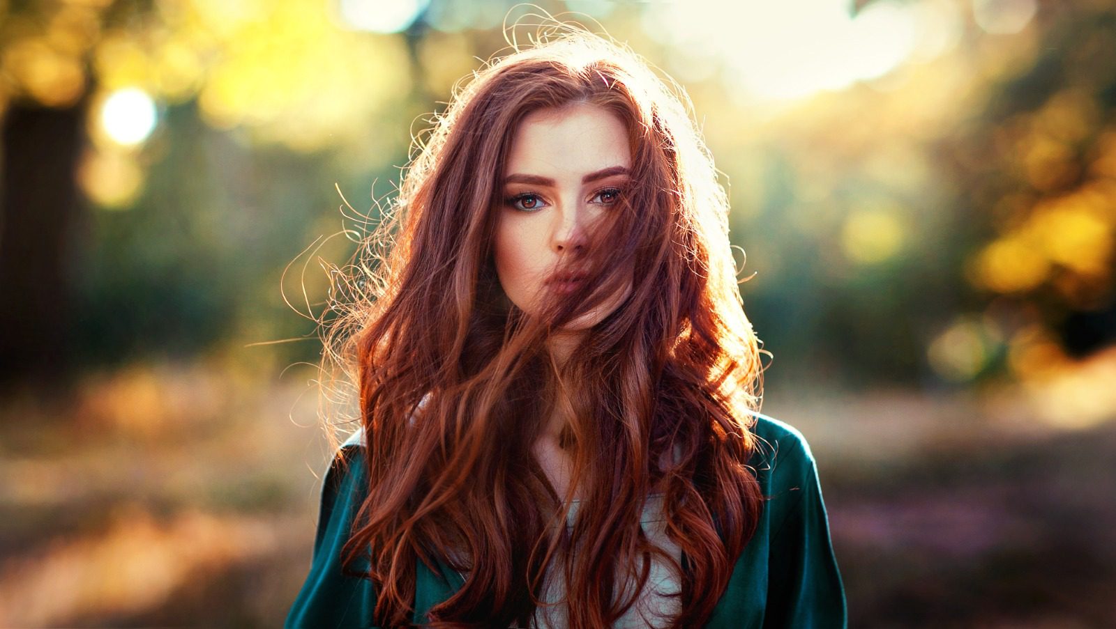 A woman with long red hair blowing in the wind.