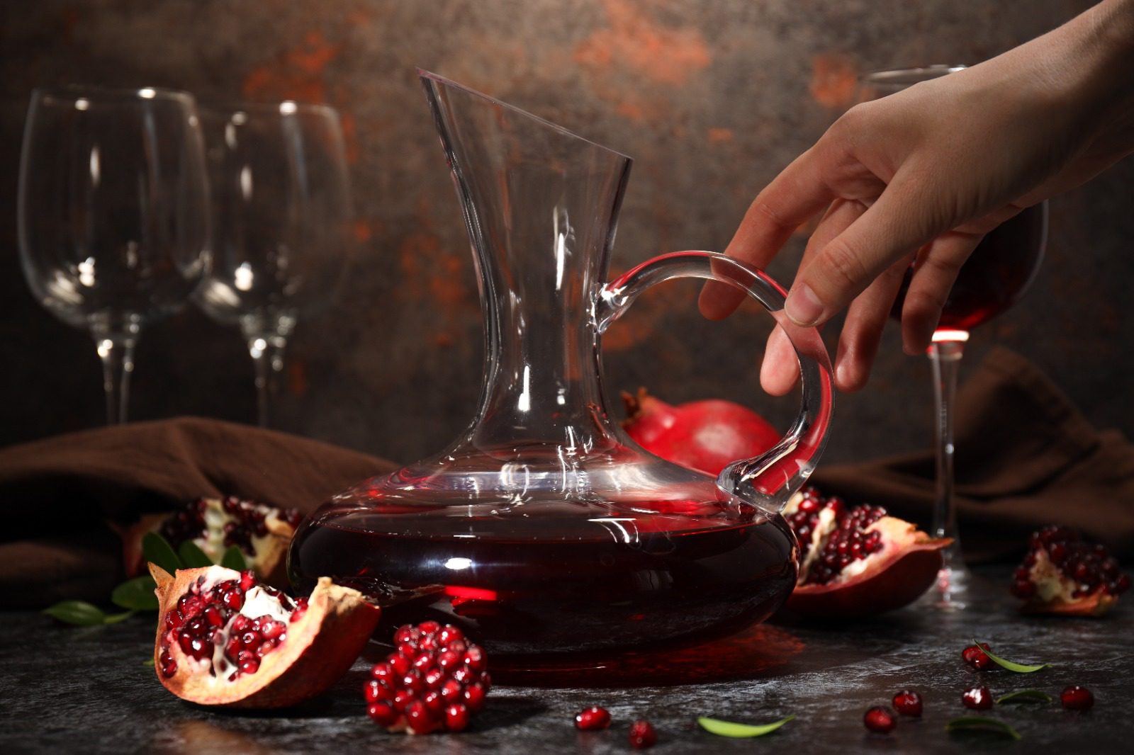 A person is pouring pomegranate juice into a glass.