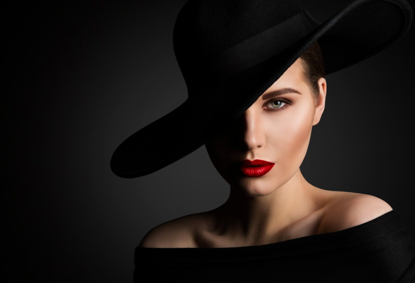 A woman with red lipstick and black hat.