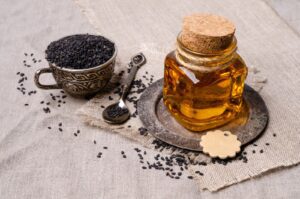 A jar of honey and some black seeds on a table.