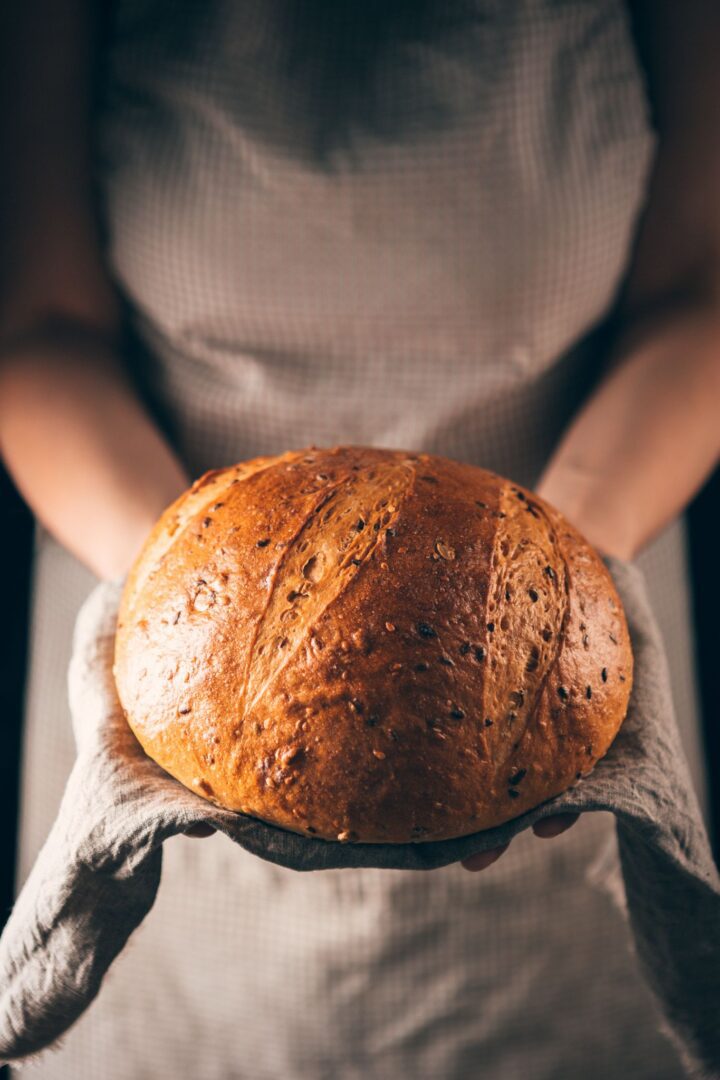 A person holding a loaf of bread in their hands.