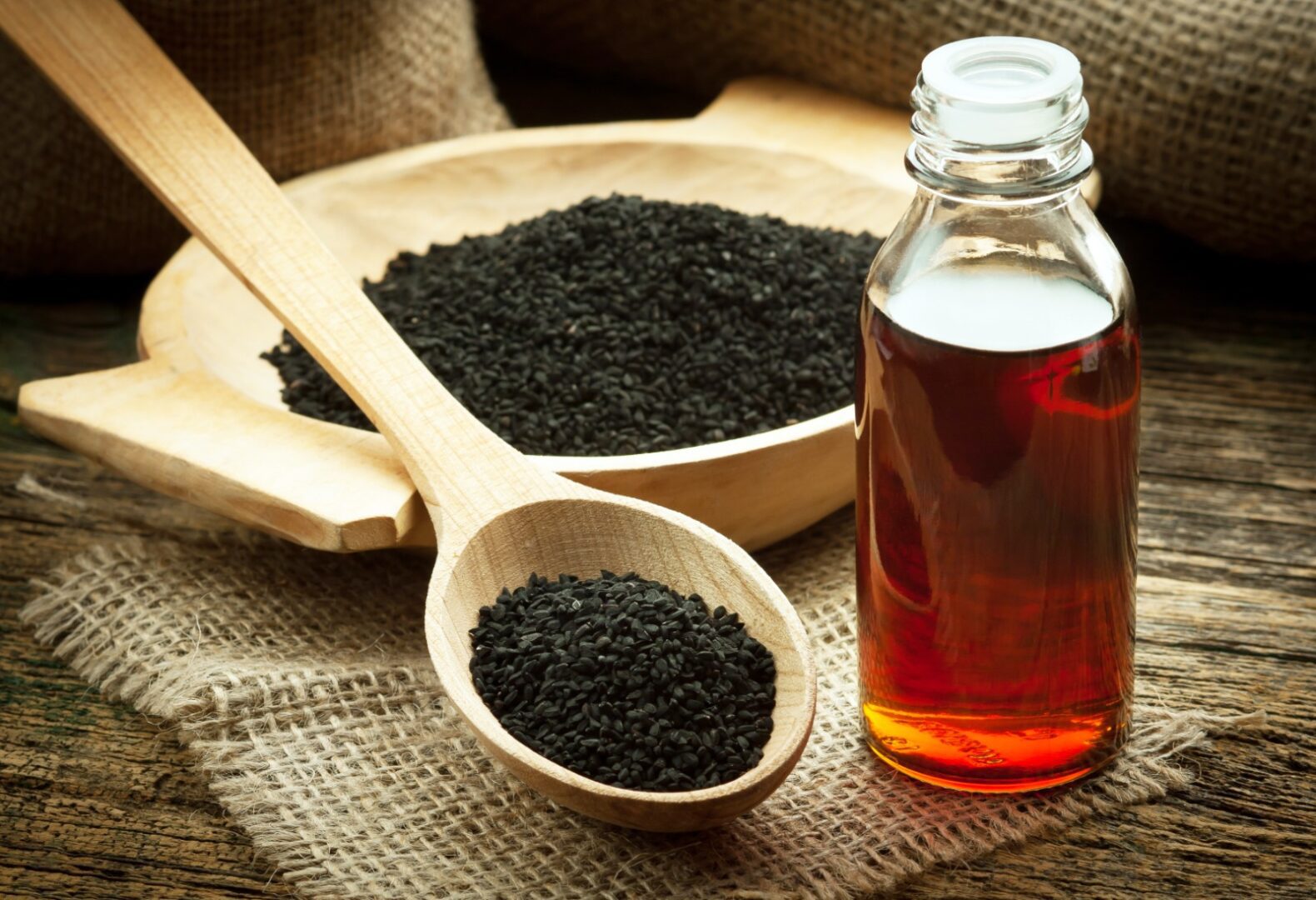 A wooden spoon filled with black tea next to a bottle of liquid.