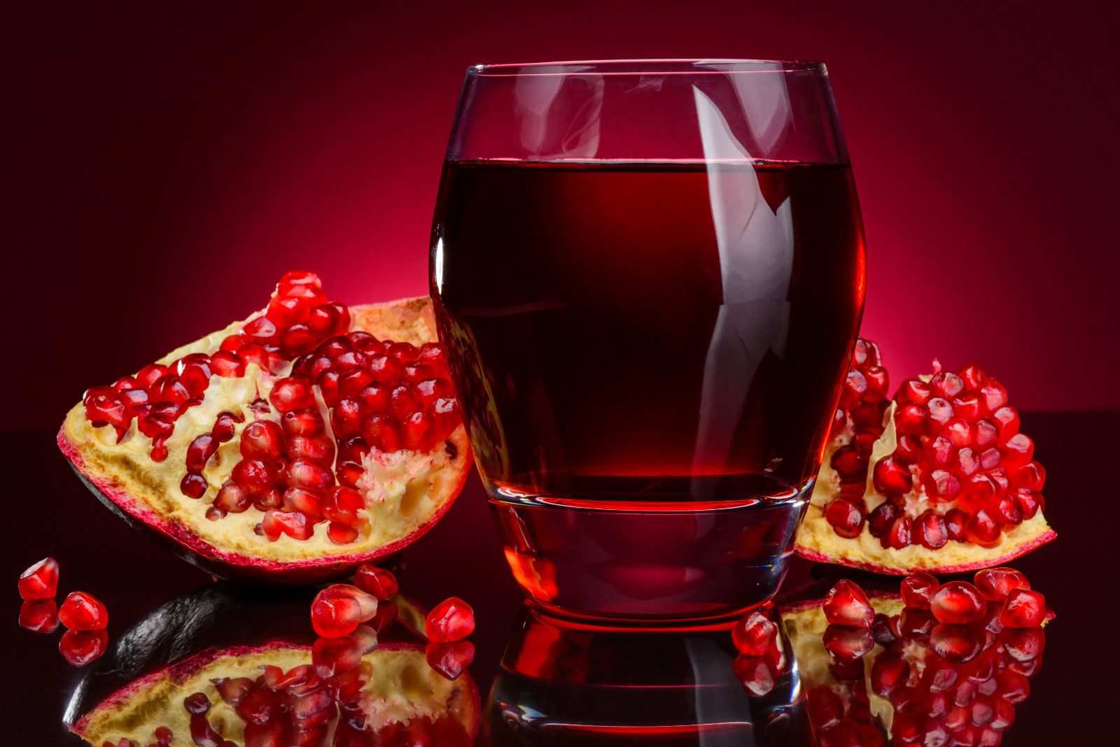 A glass of juice and some pomegranate on the table