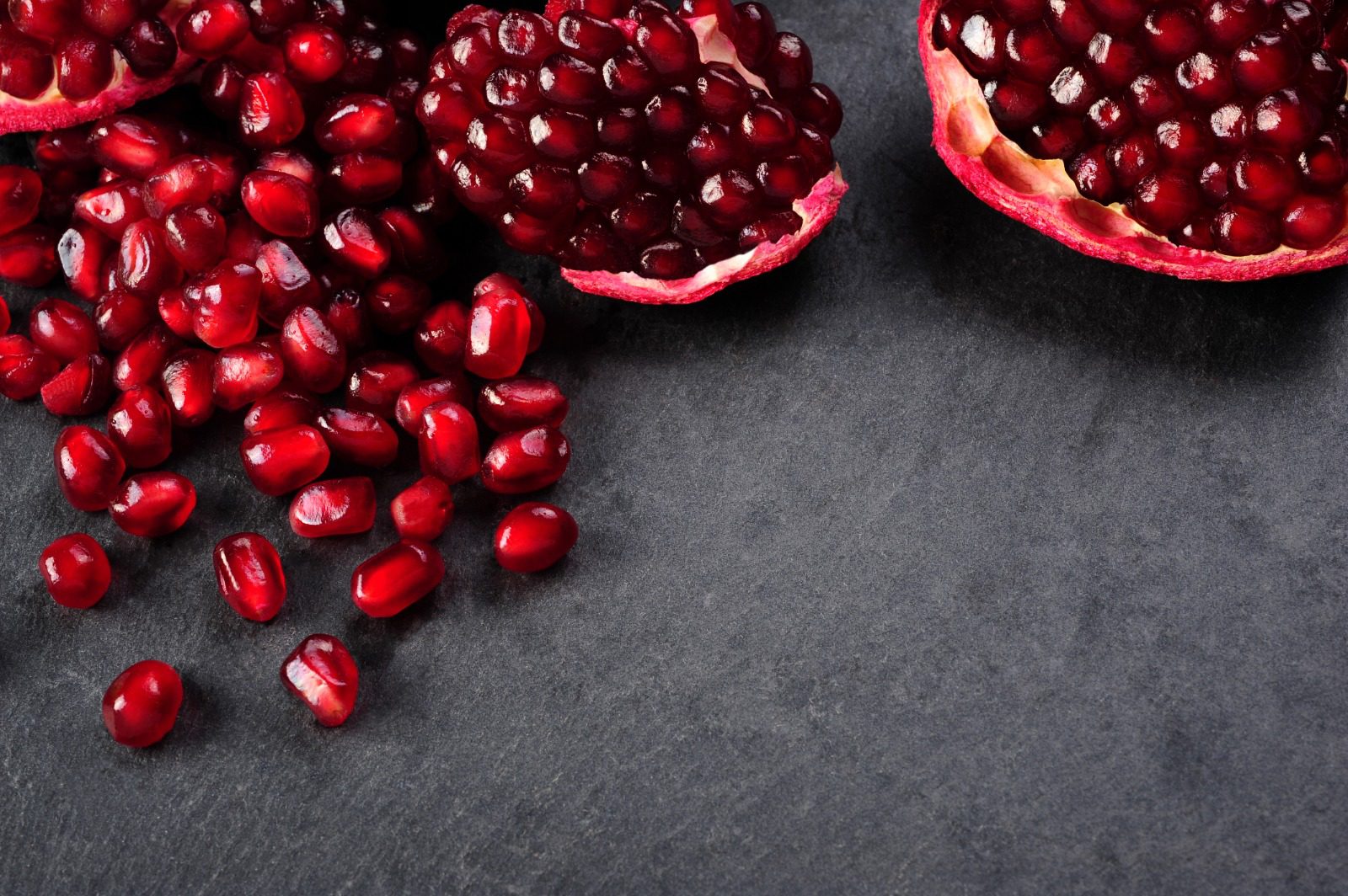 A table topped with two halves of pomegranate.