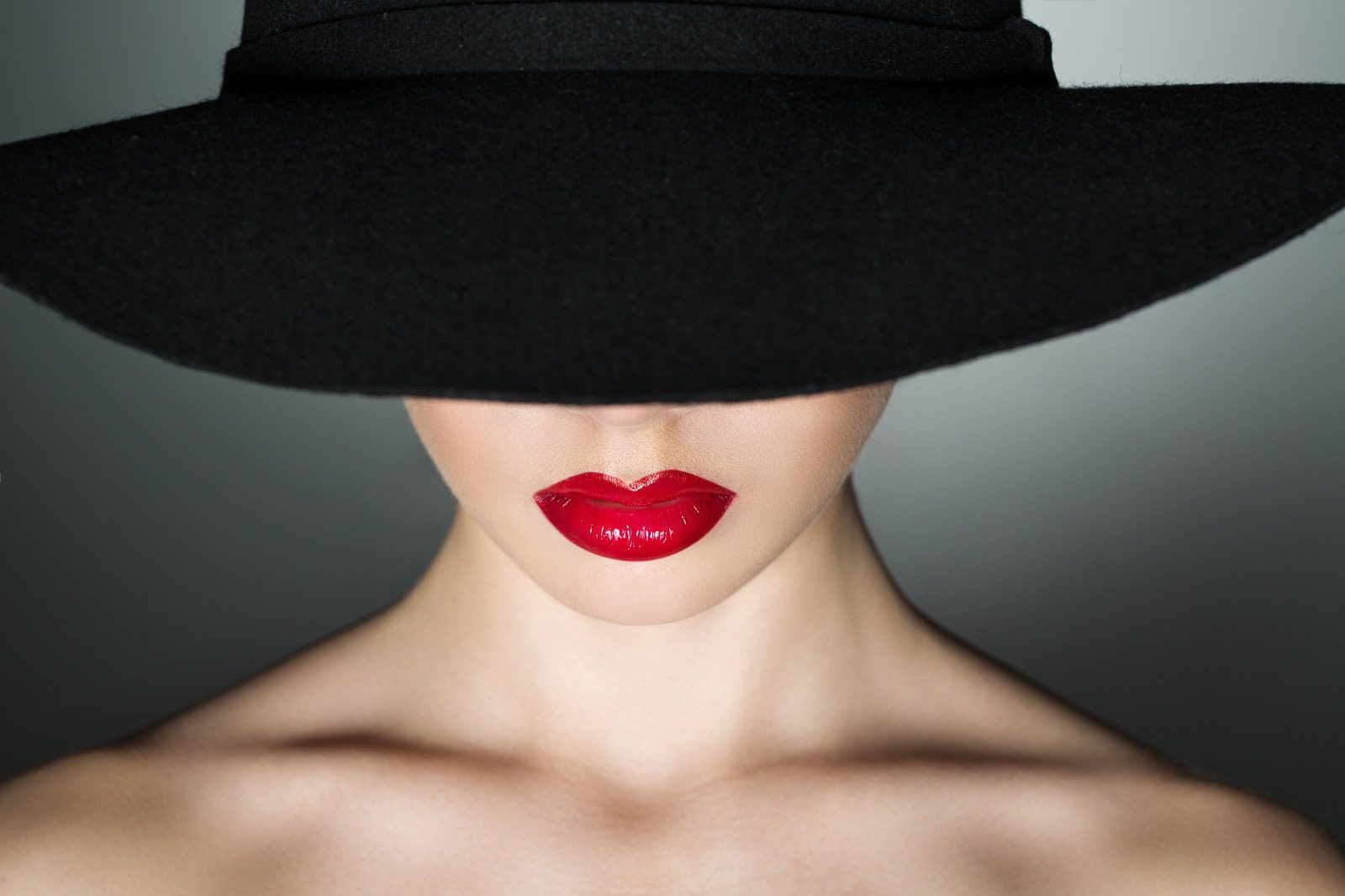 A woman with red lipstick and black hat.