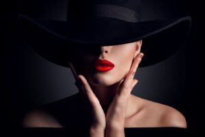 A woman with red lipstick and black hat.