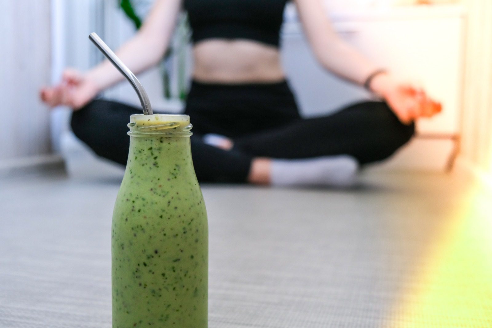 A bottle of green smoothie sitting on the floor.