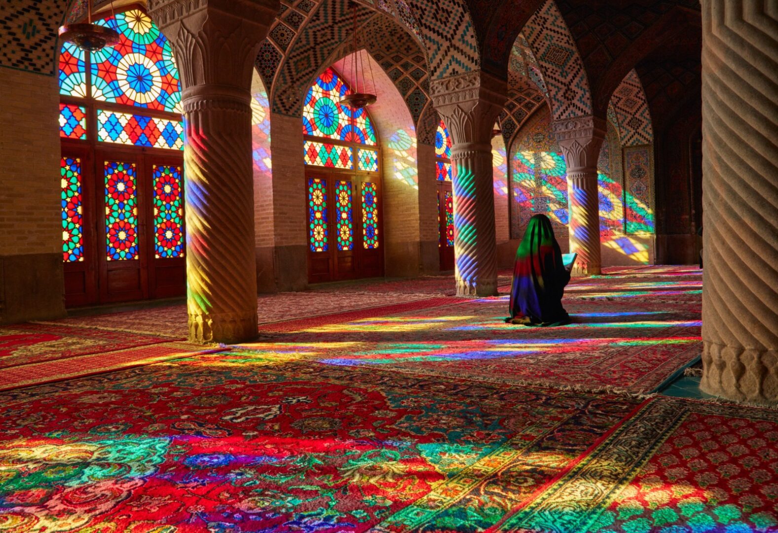 A woman sitting in the middle of a room with stained glass windows.