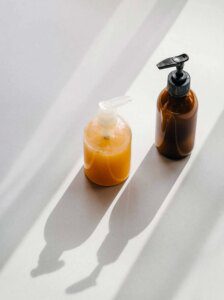 A bottle of liquid and a soap dispenser on the floor.