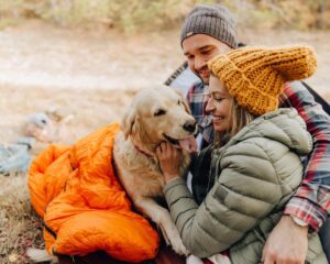 A man and woman sitting on the ground with their dog.