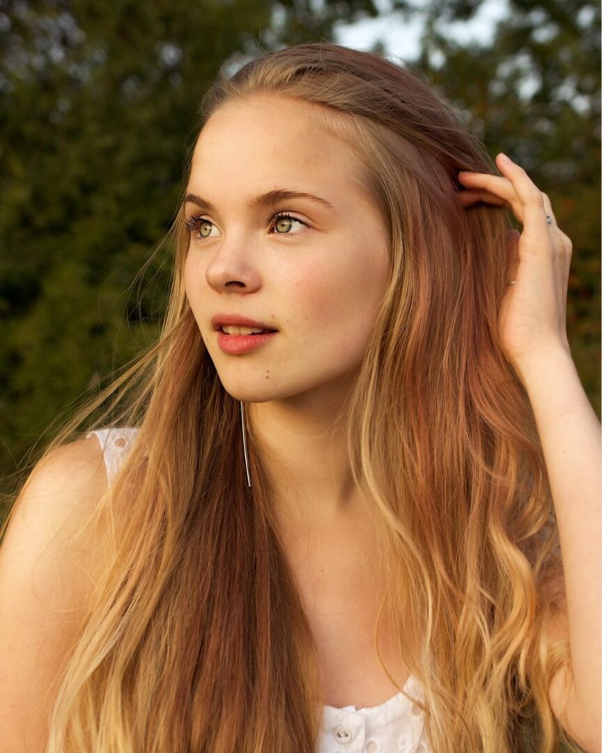 A woman with long hair is standing outside.