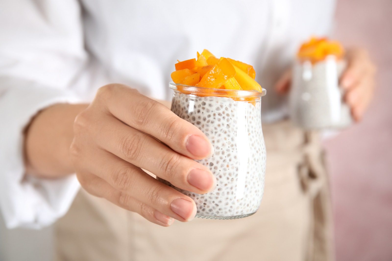 A person holding a glass of food in front of them.