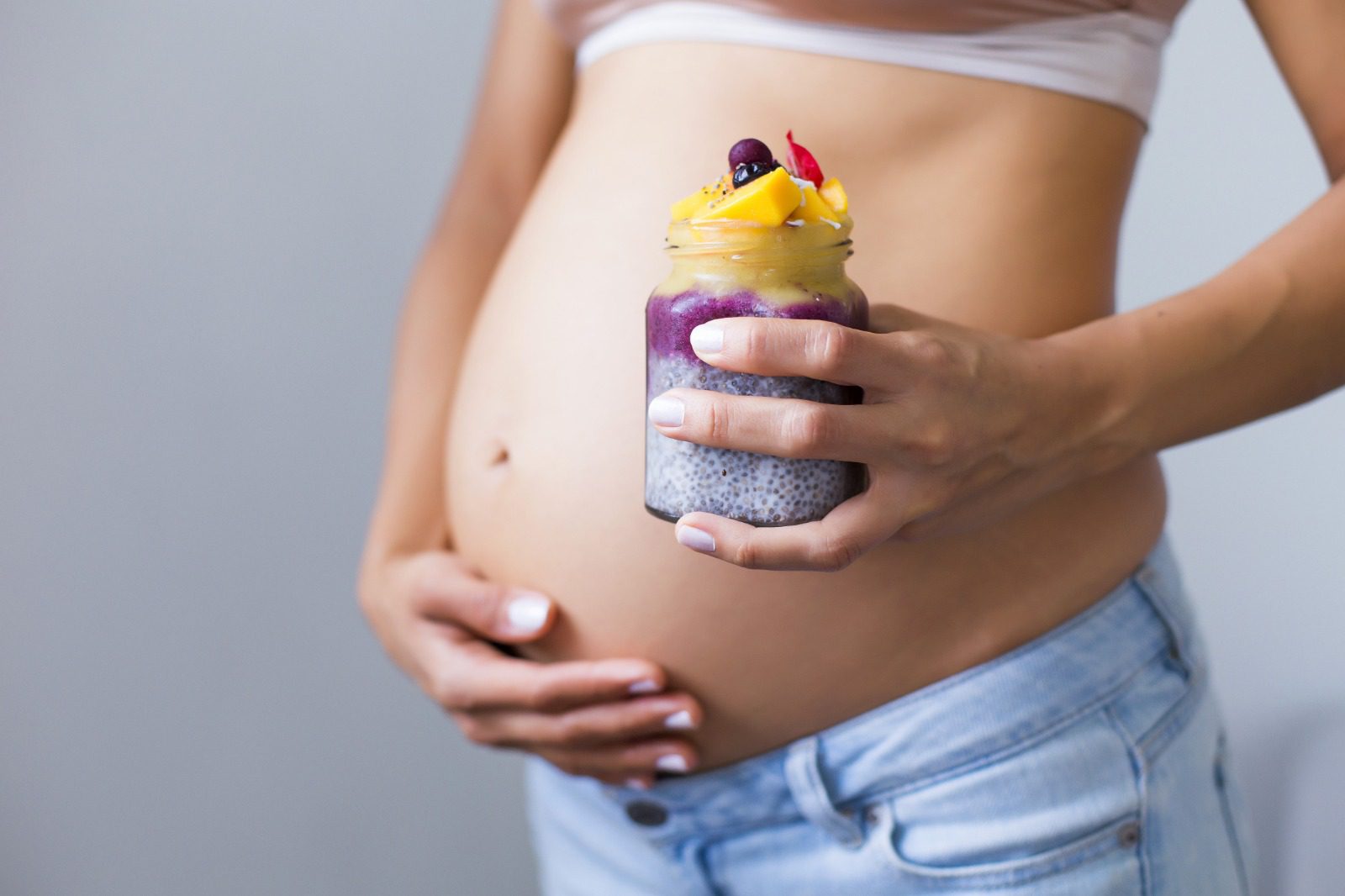 A pregnant woman holding a smoothie in her hand.