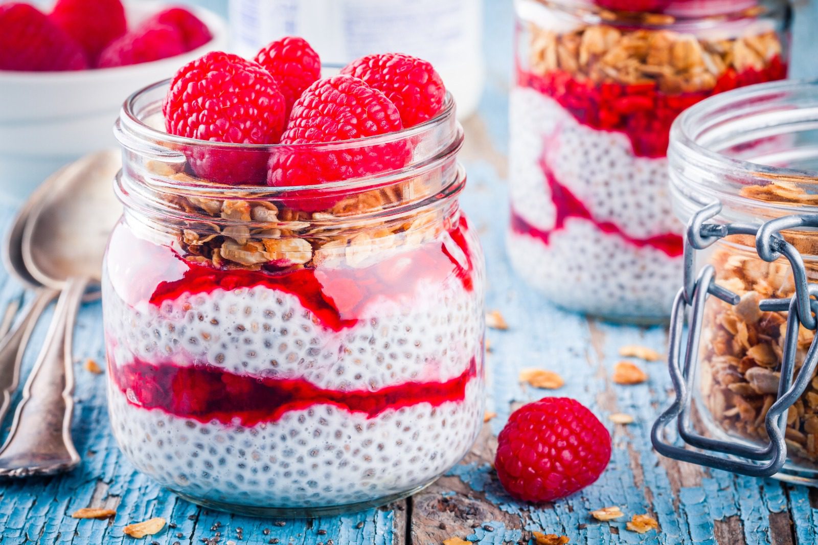 A jar of yogurt with raspberries and granola.