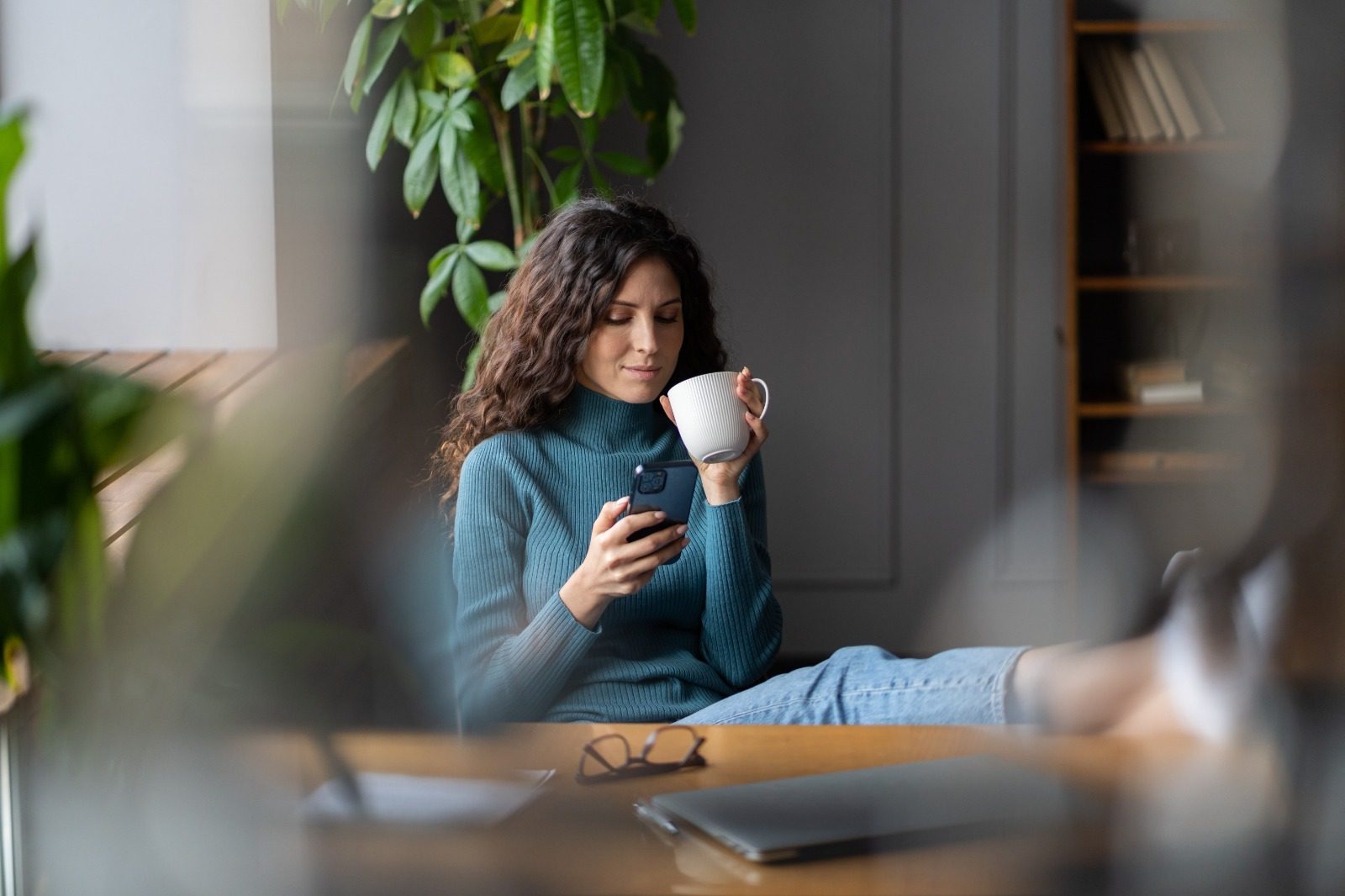 A woman sitting on the ground holding a cup of coffee.